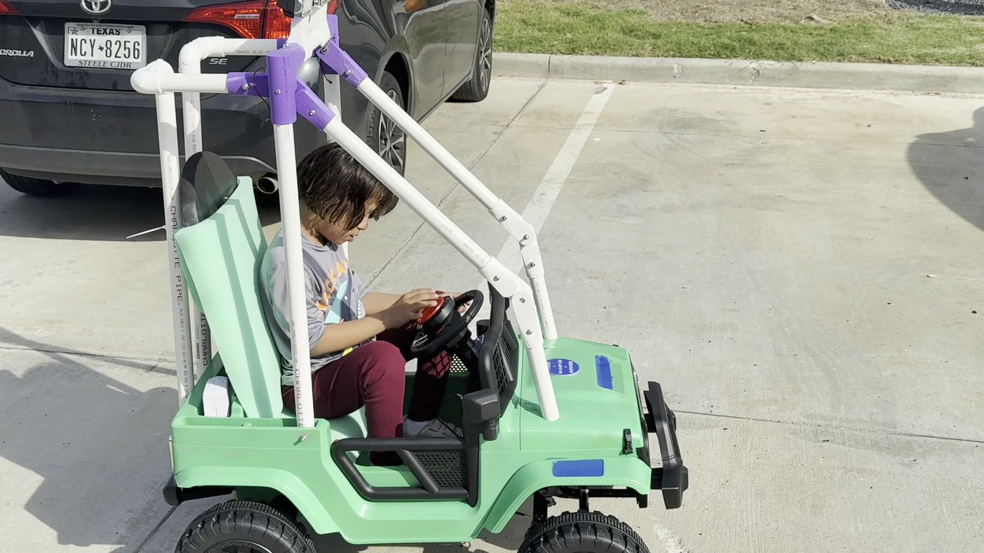 Azah driving the ride-on car ITKAN students rebuilt for her