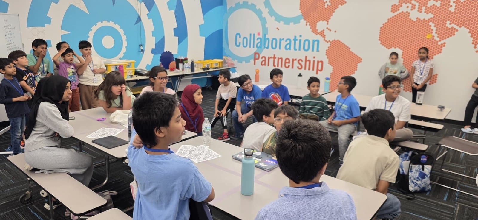 ITKAN students sit in a group trading ideas and sketching innovation-project posters