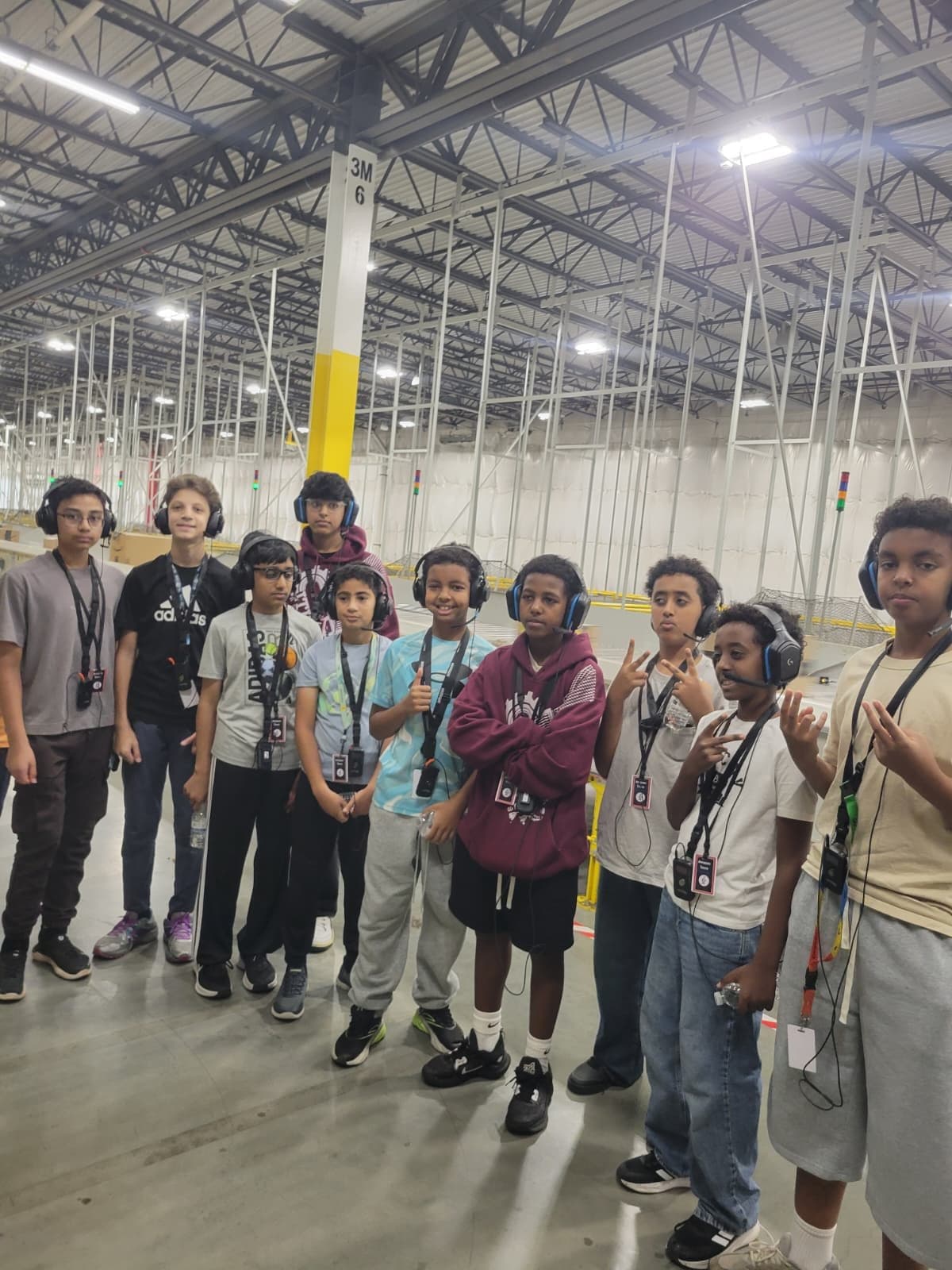 Team members in tour headsets and lanyards stand together inside an Amazon warehouse