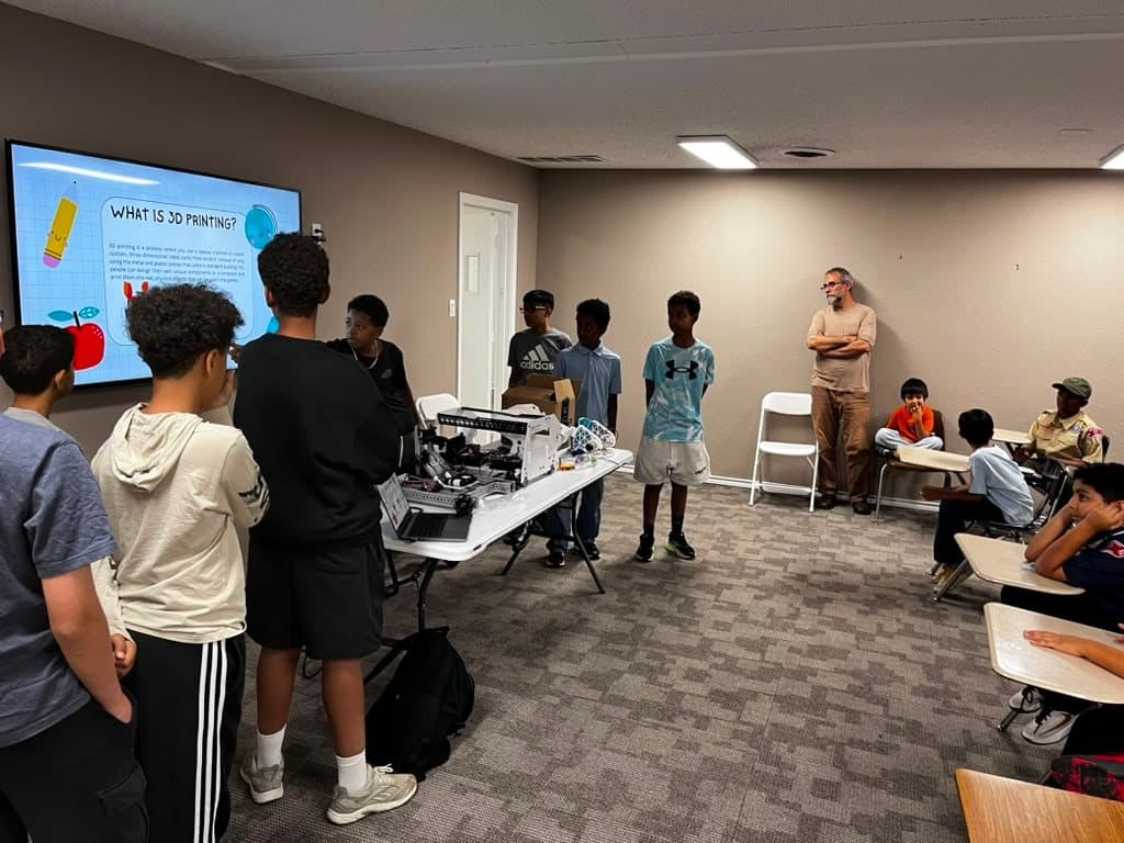 Team members present the robot to younger scouts, with a slide on the screen behind them