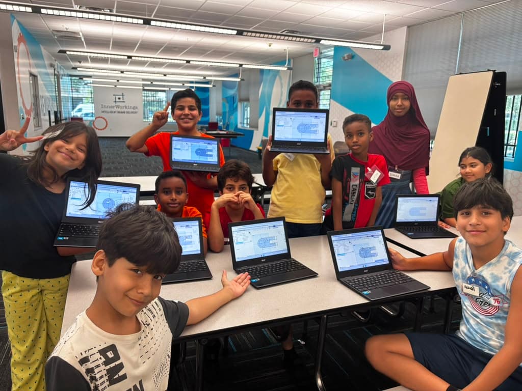 Ma'ruf community students hold up laptops showing their Onshape CAD sketches at the ITKAN Innovation Hub