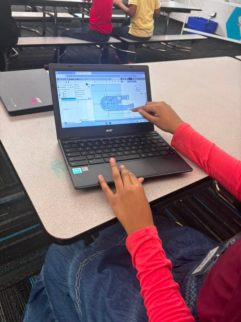 A Ma'ruf camp student points at a dimensioned Onshape sketch on a laptop screen