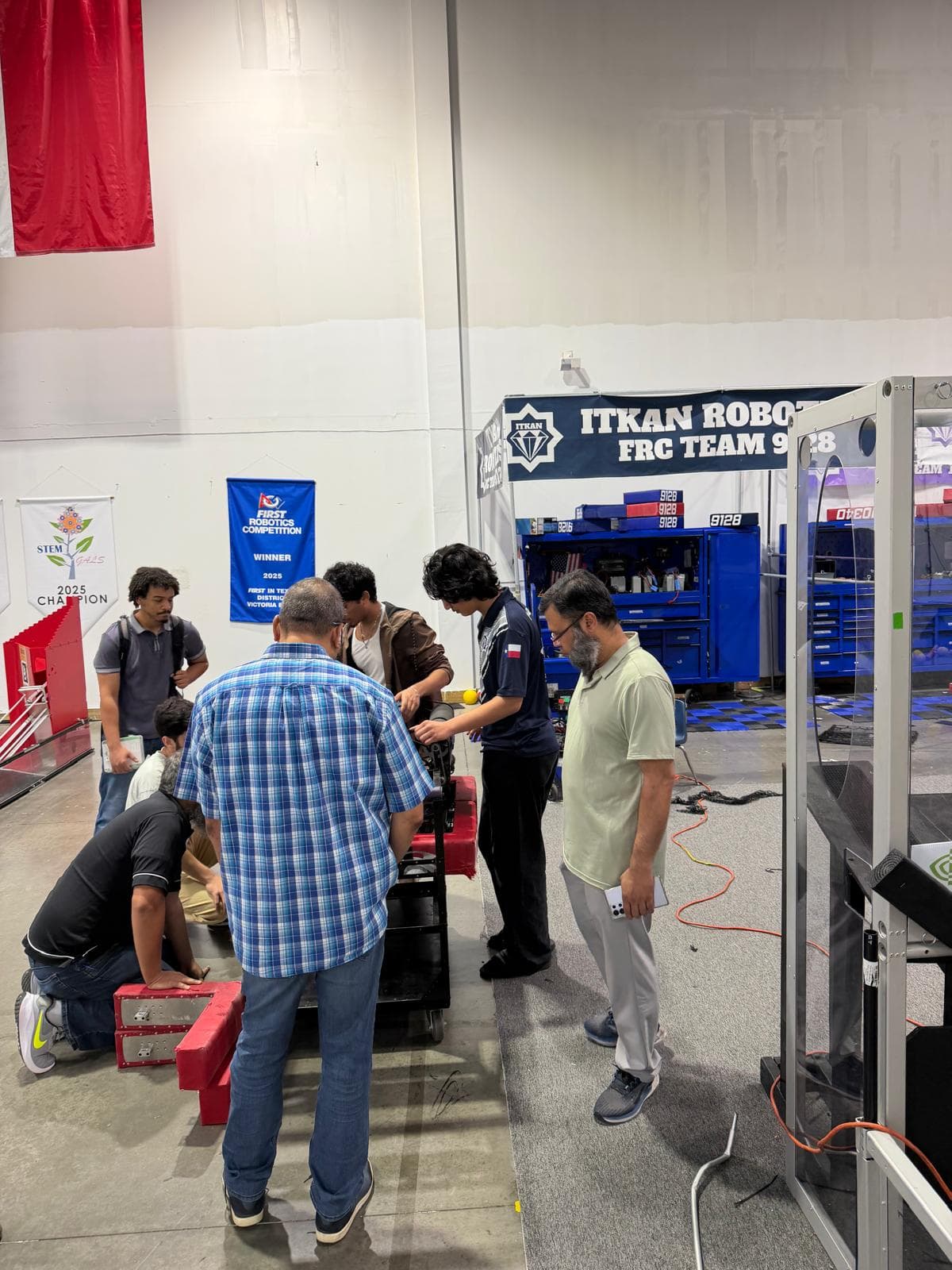 Texas Instruments engineers and ITKAN students gathered around the FRC robot at the Innovation Hub