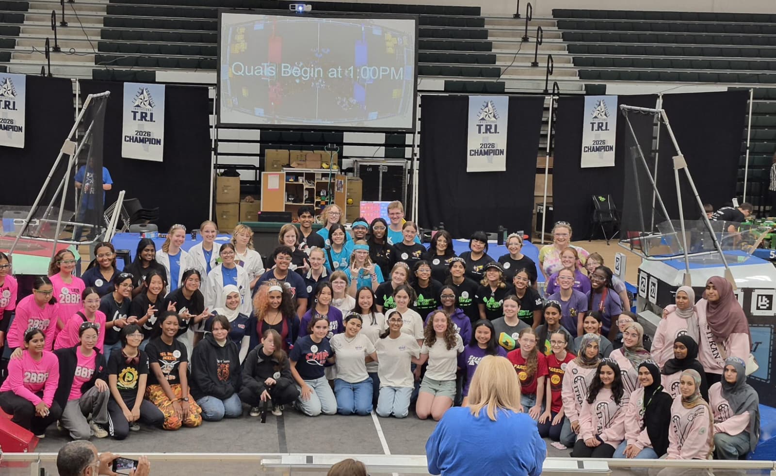 A large group photo of all girls-team participants gathered on the TRI competition floor as qualifications are announced